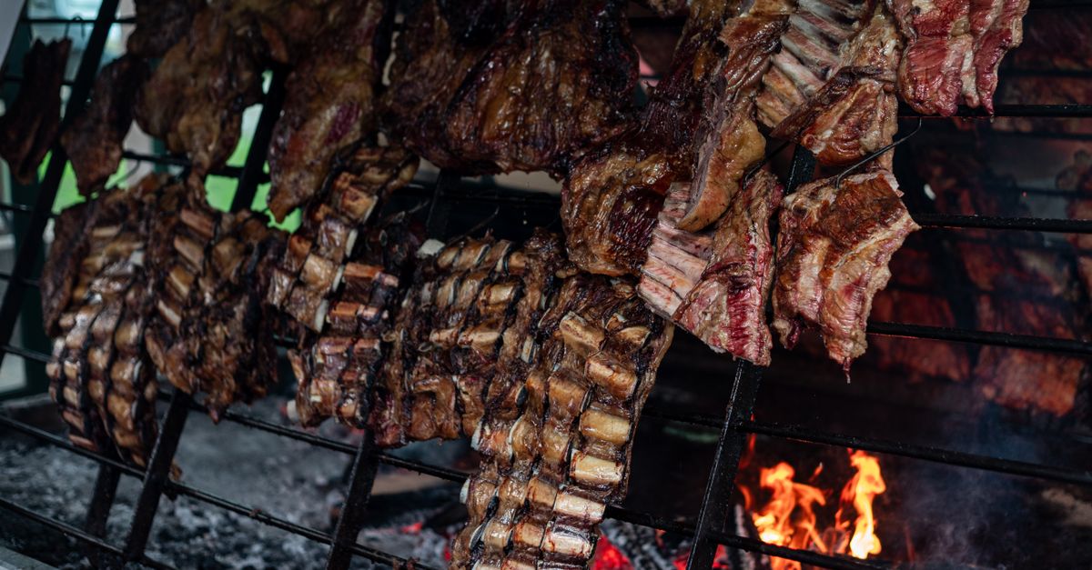 Parrilla con cortes de carne sellandose sobre brasas